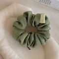 Primo piano dettagliato di un simpatico scrunchie di stoffa verde a pois con etichetta. - Anello per Capelli a Pois / Verde