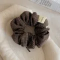 Primo piano dettagliato di un elastico per capelli in tessuto marrone a pois con etichetta. - Anello per Capelli a Pois / Caffè