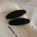 Primo piano di fermagli per capelli in tessuto nero con pois bianchi, accessorio quotidiano. - Molla per Capelli a Pois / 1 Pezzo / Nero
