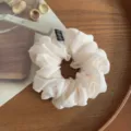 Vista detallada de un coletero de gasa blanca para el cabello con etiqueta negra, elegante. - Blanco Roto
