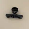 Gros plan de la pince à cheveux noire brillante, avec un design croisé élégant et soigné. - Pince Crabe Croisée Moyenne (Noir) / Noir