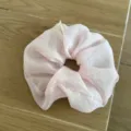 Close-up detail of a pink gingham sheer fabric hair scrunchie showcasing its soft texture. - Pink