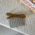 Primer plano del peine de acetato marrón con lazo y dientes metálicos, detalle. - Café Claro