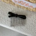 Detalle en primer plano de un elegante peine para el pelo con lazo de acetato negro. - Negro