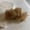 Close-up of a Korean style fluffy leopard print organza bow hair clip detail on texture. - Coffee