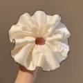 Close-up van elegante beige satijnen haarscrunchie met donkerbruine geschulpte rand. - Klassiek Haarelastiekje / Witte Scrunchie
