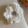 Primer plano detallado de un coletero blanco con lunares negros y borde con volantes. - Blanco Roto