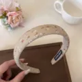Vue détaillée du joli serre-tête floral, avec de petites fleurs sur un tissu beige. - Khaki