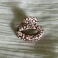 Close-up of elegant oval hair claw clip with unique tortoiseshell mosaic pattern design. - Textured Pink