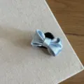 Primer plano detallado de una pinza para el pelo con lazo de satén azul claro elegante. - Azul