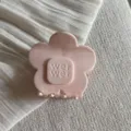 Gros plan de la pince à cheveux rose clair en forme de fleur, montrant de fins détails. - Rose
