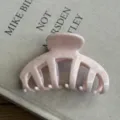 Close up of a retro pink acetate hair claw clip, featuring a large design for thick hair styling. - Pink