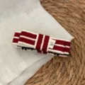 Close-up detail of red and white striped knit hair claw clip with a cute fabric label tag. - Banana Clip / Red