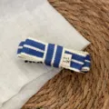 Blue and white striped fabric hair clip detail shot showing the woven texture and bow label. - Banana Clip / Blue