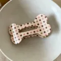 Close-up view of cute polka dot bone-shaped hair claw clip, pink aesthetic accessory detail. - Brown Polka Dot Bone