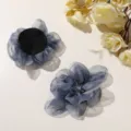 Primer plano del accesorio para el cabello de flor de organza gris azulado con textura delicada. - Azul
