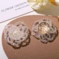 Detailed close-up of clear beaded flower DIY accessory with pearl and golden button decor. - One Flower