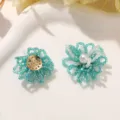 Primer plano de flores de cuentas azules y blancas hechas a mano, ideal para pendientes y accesorios. - Azul Pavo Real