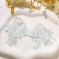 Detailed close-up of handmade beaded flower tassel DIY accessories in white and blue tones. - Blue