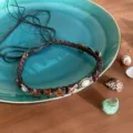 Detailed shot of bohemian style braided rope necklace with wooden star beads and pearl charm. - Style F