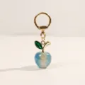 Blue acrylic apple keychain with gold hardware and green crystal leaf charm for bags. - Blue