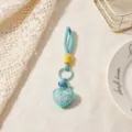 Close up of a cute blue heart keychain with strap and bell, ideal bag charm accessory. - Blue