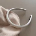 Gros plan détaillé du serre-tête blanc matelassé minimaliste avec texture satinée. - Blanc Cassé