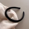 Détail de serre-tête en satin noir en gros plan montrant un tissu lisse et un style épuré. - Noir