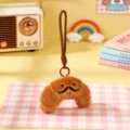 Close-up detail of the cute plush croissant keychain with funny mustache, soft texture accessory. - Croissant