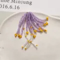 Dettaglio di nappa di perline viola e gialle fatte a mano, delicato accessorio per gioielli DIY. - Viola
