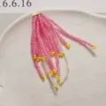 Detalle de primer plano de material artesanal de borlas de cuentas rosas y amarillas para flores. - Rosa