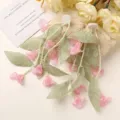 Detalle de primeros planos de pendientes lirio de los valles con encaje verde y flores. - Rosa