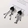 Detailed close-up view of unique black grey jellyfish beaded tassel earrings with fine beadwork. - Black