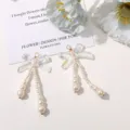 Detailed view of iridescent bow earrings with hanging pearl strands, handmade jewelry. - AB White