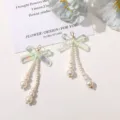 Close-up view of DIY iridescent acrylic bow pendants featuring delicate pearl chains. - Aurora Green