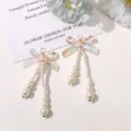 Primer plano del detalle de pendientes de perlas con lazo iridiscente, resina y perlas. - Rosa Iridiscente