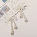 Elegantes pendientes largos de perlas con lazo iridiscente para un look otoñal chic. - Verde con Brillo