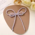 Close-up detail of the elegant purple imitation pearl bow accessory, exquisite craftsmanship. - Purple