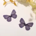 Gros plan détaillé de patchs de papillons brodés violet scintillant avec des fils métalliques. - Violet