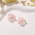 Detailed close-up of pink crystal flower DIY stud earrings and accessories on a white plate. - Pink