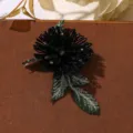 Vue détaillée d'un patch brodé de fleurs perlées noires avec des feuilles vertes. - Noir