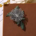 Vista dettagliata della spilla di fiori con perline in filo d'argento e foglie ricamate. - Grigio