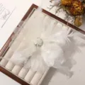 Primer plano de pinza para pelo artesanal de plumas blancas con perlas y pedrería. - Beige