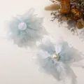 Close-up detail of light green tulle flower DIY accessory with white feathers and pearls. - Green