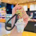Iridiserende gelukskat sleutelhanger met een gevlochten lederen band en gouden ring. - Zwart
