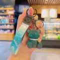 Cute cartoon bear keychain with gradient blue strap and bell pendant for backpack or keys. - Green