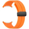 Detailed view of orange silicone watch strap with black magnetic folding buckle and connectors. - Orange