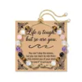 Detail view of adjustable natural stone bead bracelet with a metal wave charm on card. - Inspirational - Life Is Tough But So Are You