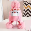 Childrens pink knit beanie winter hat with reindeer pattern, cute pom pom earflap design. - Pink