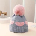 Baby knit hat detail showing cute pink heart pattern, cozy pom pom and soft texture. - Gray